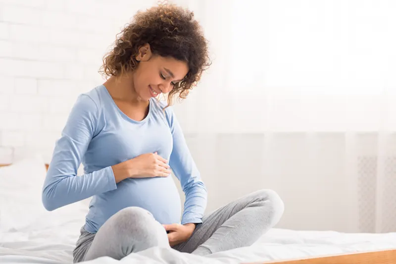 Schwangere Frau hält sich den Bauch